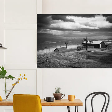 Glencoe Mountain View wall art showing a black and white panorama from Glencoe Mountain with ski lifts, small huts and a wide Highland landscape under dramatic clouds
