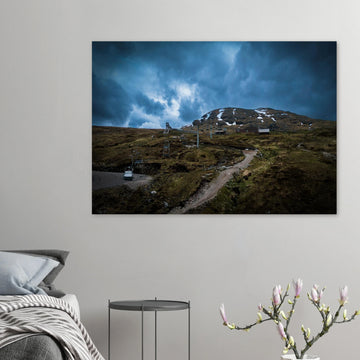 Glencoe Ski Lift wall art showing empty chairlifts climbing a rugged hillside towards snow patches with dramatic blue-grey clouds over Glencoe Mountain Resort