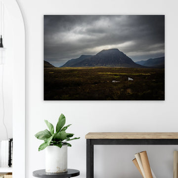 Buachaille Etive Mòr stormy sunrise wall art showing the dark Glencoe mountain under heavy clouds with a strip of light over the foreground moorland