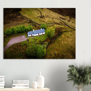 Blackrock Cottage Glencoe wall art showing an aerial view of the long white cottage with red doors surrounded by green moorland, trees and winding tracks