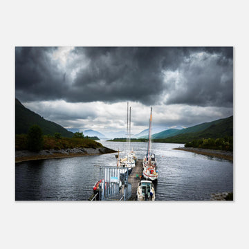 Ballachulish Harbour wall art showing yachts lined up along a narrow pier between green hills with dark storm clouds over the Scottish waterway