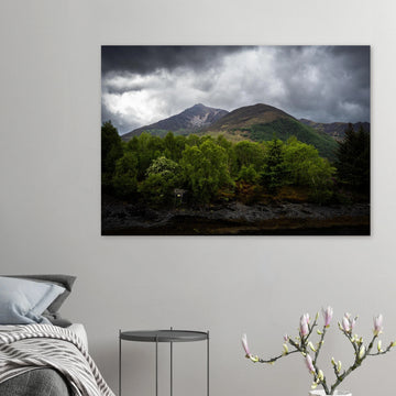 Glencoe and Glen Etive wall art showing bright green trees in front of rocky Highland mountains under dark storm clouds in the Scottish glen