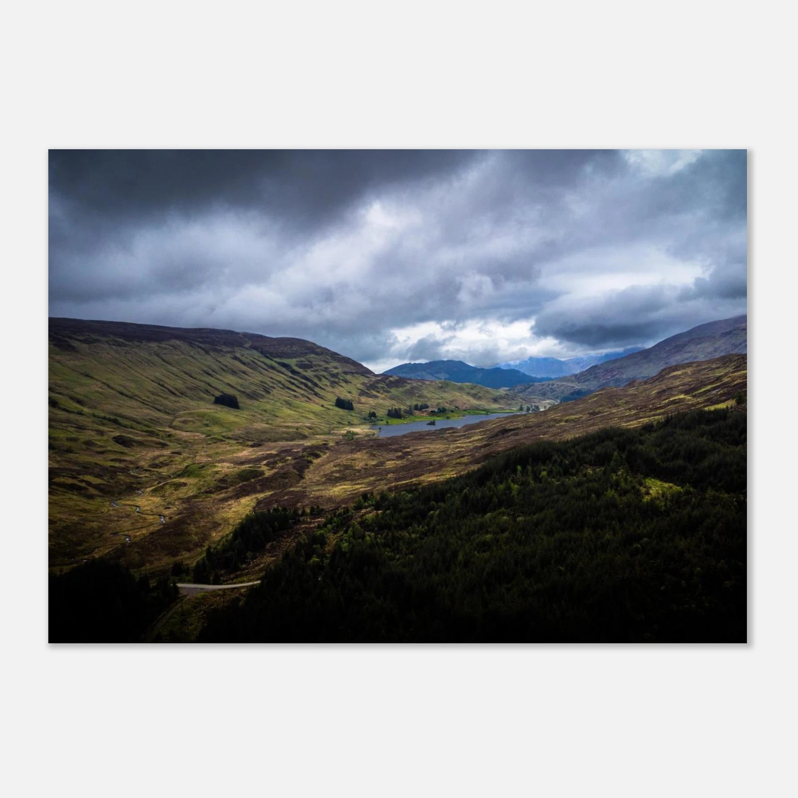 Scottish Highlands Glen wall art showing a rugged valley with rolling heather hills, a small loch and heavy storm clouds over the remote Scottish landscape