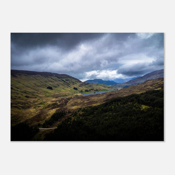 Scottish Highlands Glen wall art showing a rugged valley with rolling heather hills, a small loch and heavy storm clouds over the remote Scottish landscape