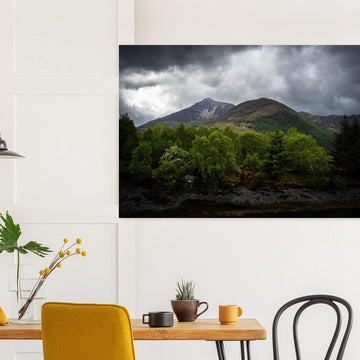 Glencoe and Glen Etive wall art showing bright green trees in front of rocky Highland mountains under dark storm clouds in the Scottish glen