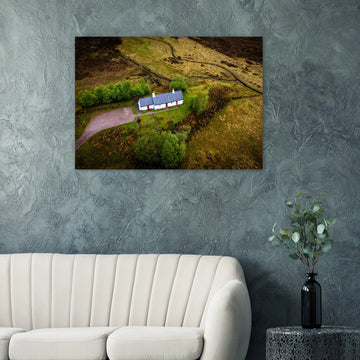 Blackrock Cottage Glencoe wall art showing an aerial view of the long white cottage with red doors surrounded by green moorland, trees and winding tracks