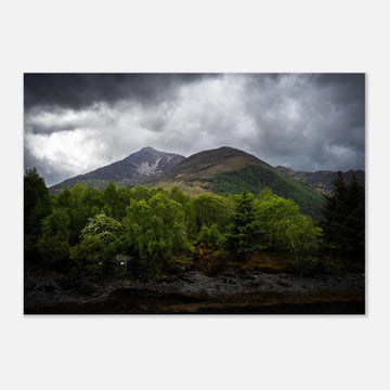 Glencoe and Glen Etive wall art showing bright green trees in front of rocky Highland mountains under dark storm clouds in the Scottish glen