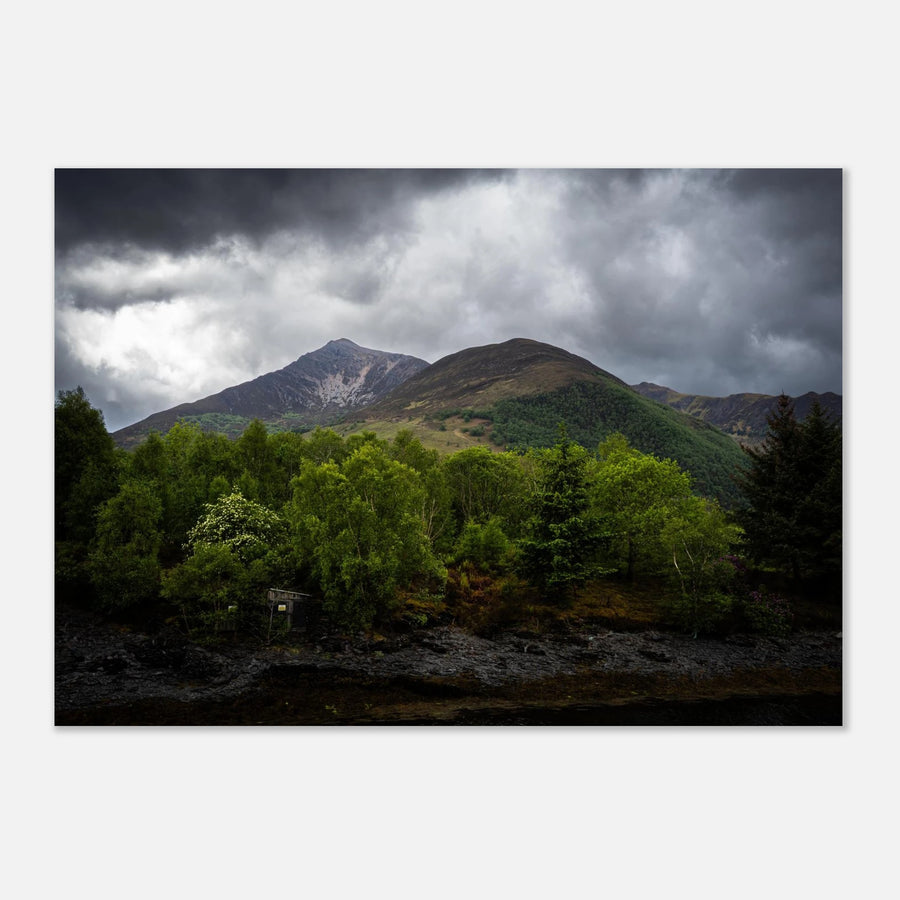 Glencoe and Glen Etive wall art showing bright green trees in front of rocky Highland mountains under dark storm clouds in the Scottish glen
