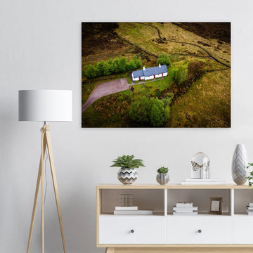 Blackrock Cottage Glencoe wall art showing an aerial view of the long white cottage with red doors surrounded by green moorland, trees and winding tracks