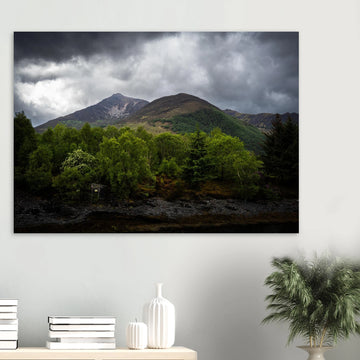 Glencoe and Glen Etive wall art showing bright green trees in front of rocky Highland mountains under dark storm clouds in the Scottish glen