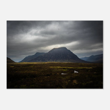 Buachaille Etive Mòr stormy sunrise wall art showing the dark Glencoe mountain under heavy clouds with a strip of light over the foreground moorland