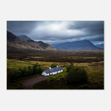 Blackrock Cottage Buachaille Etive Mòr wall art showing the white cottage in front of a dramatic Scottish Highlands mountain under dark storm clouds and moody light