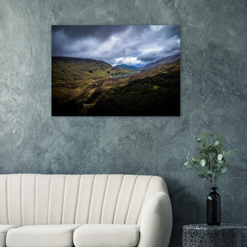 Scottish Highlands Glen wall art showing a rugged valley with rolling heather hills, a small loch and heavy storm clouds over the remote Scottish landscape