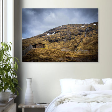 Glencoe Mountain Ski Lift Top wall art showing a wooden hut and fences on a rocky hillside with ski lift towers, snow patches and grey clouds at Glencoe Mountain Resort