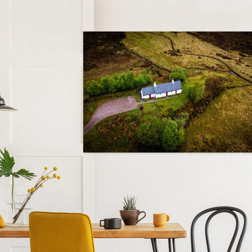 Blackrock Cottage Glencoe wall art showing an aerial view of the long white cottage with red doors surrounded by green moorland, trees and winding tracks