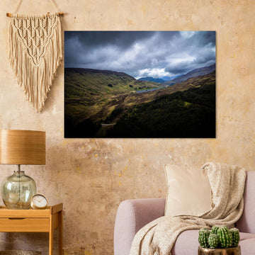 Scottish Highlands Glen wall art showing a rugged valley with rolling heather hills, a small loch and heavy storm clouds over the remote Scottish landscape