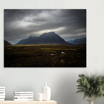 Buachaille Etive Mòr stormy sunrise wall art showing the dark Glencoe mountain under heavy clouds with a strip of light over the foreground moorland