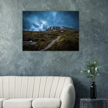 Glencoe Ski Lift wall art showing empty chairlifts climbing a rugged hillside towards snow patches with dramatic blue-grey clouds over Glencoe Mountain Resort